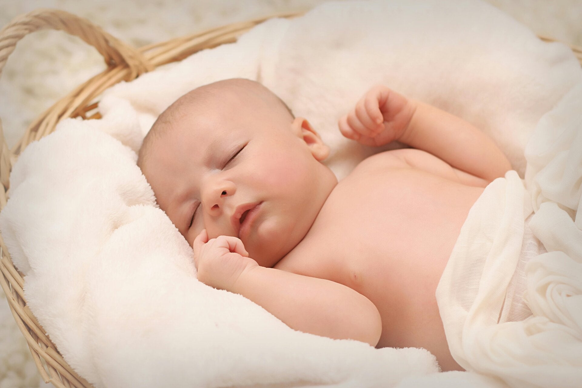 Baby slaapt tevreden in een rieten mandje op een zachte deken